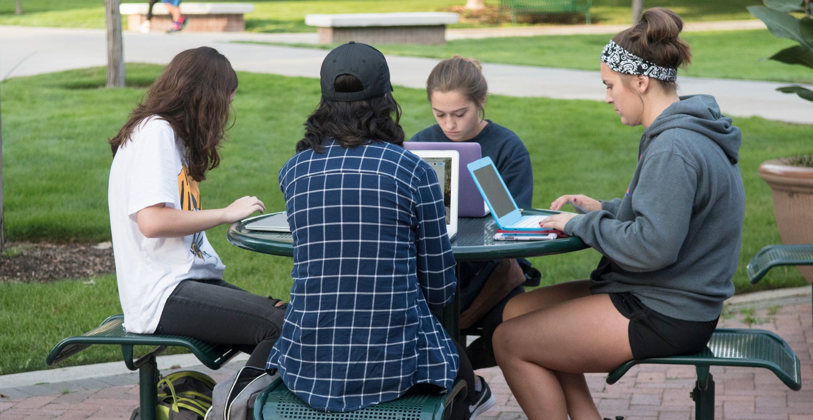 students study at table outside on campus