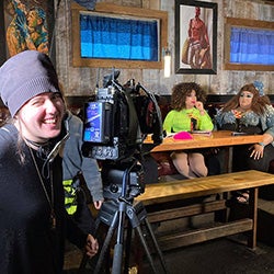 a woman cinematographer shoots two actresses in a bar