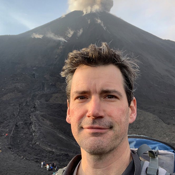 Greg Waite standing with a volcano behind him