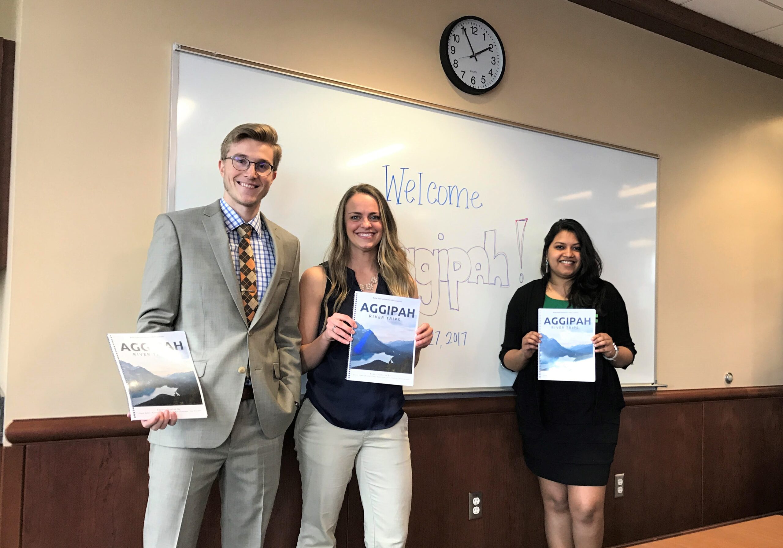 Three people hold a report with the word Aggipah on the cover