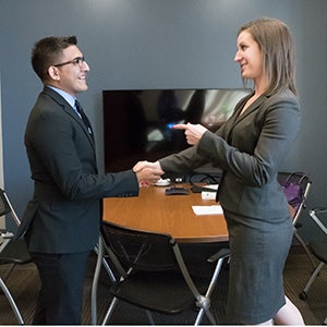 IIvan Sanchez, COBE student, shaking hands with Kelsey White, Deloitte