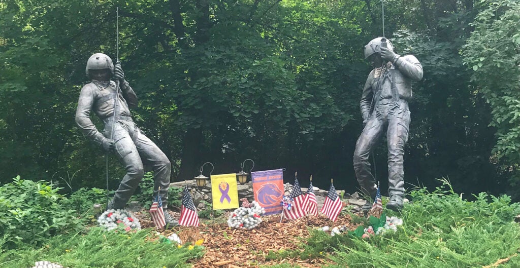 memorial statues of Jeff and Shane reppelling, visitors have placed flowers and American and Boise Sate flags at the site