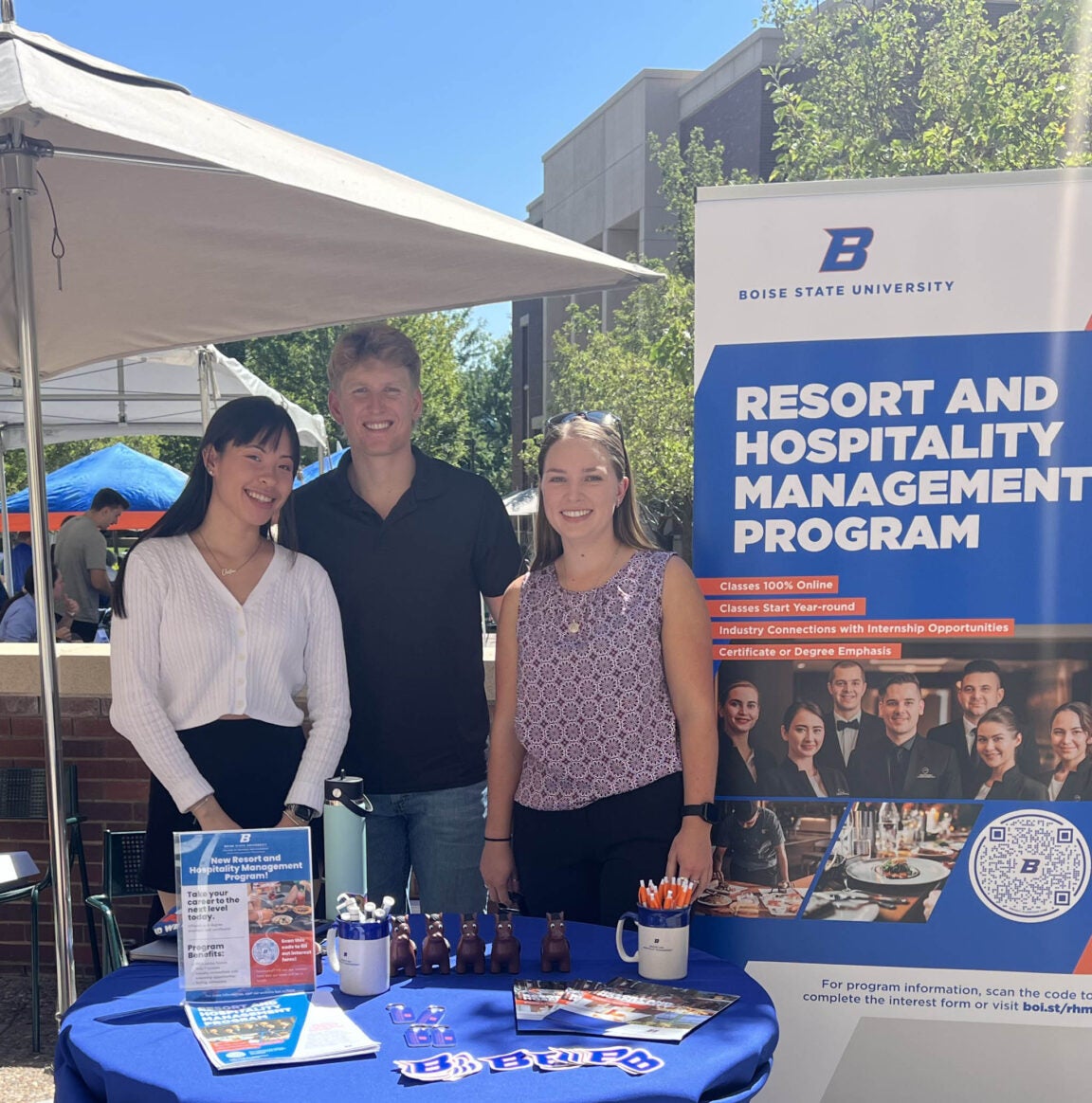 students standing by a Resort and Hospitality Management program banner