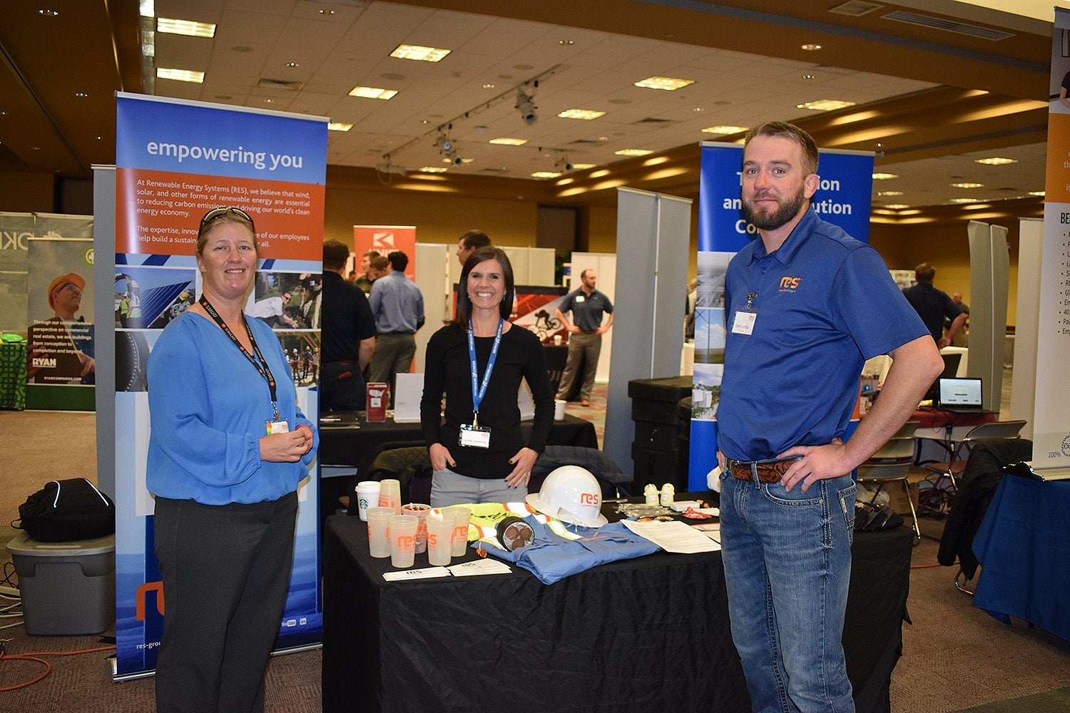 3 people standing next to a table at a career fair