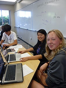 two high school girls in a classroom with laptops