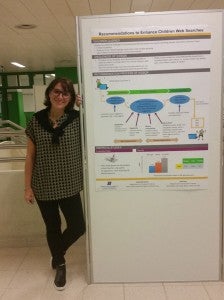 student standing next to a presentation poster