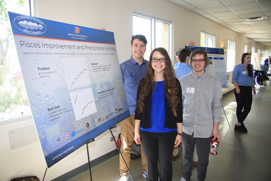 Photo of senior design team of three students standing next to their poster