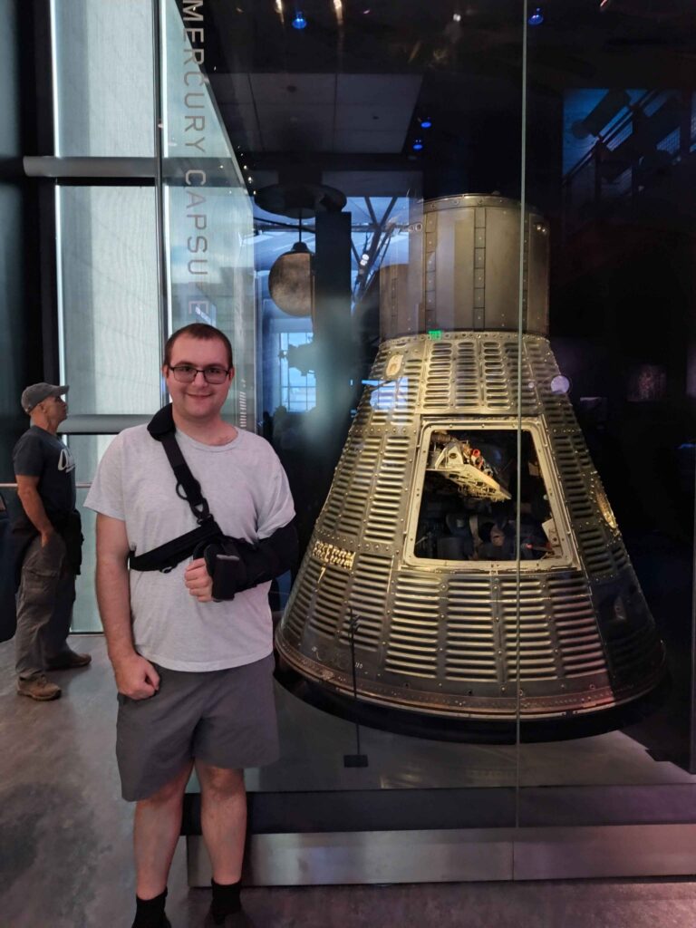 Photo of Adam Torek in next to a capsule display, in a D.C. museum.