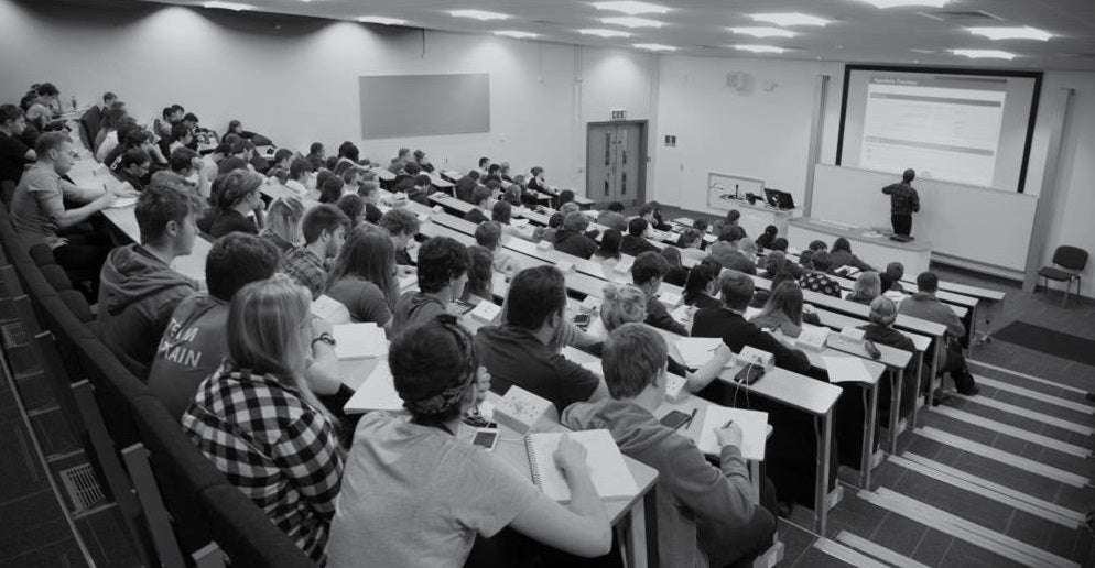 Students taking notes during a lecture in a lecture hall.