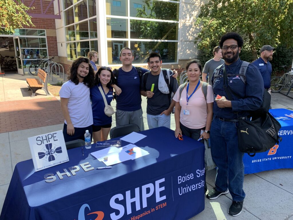 Group of students at the Society of Hispanic Professional Engineers (SHPE) booth in front of the ILC building