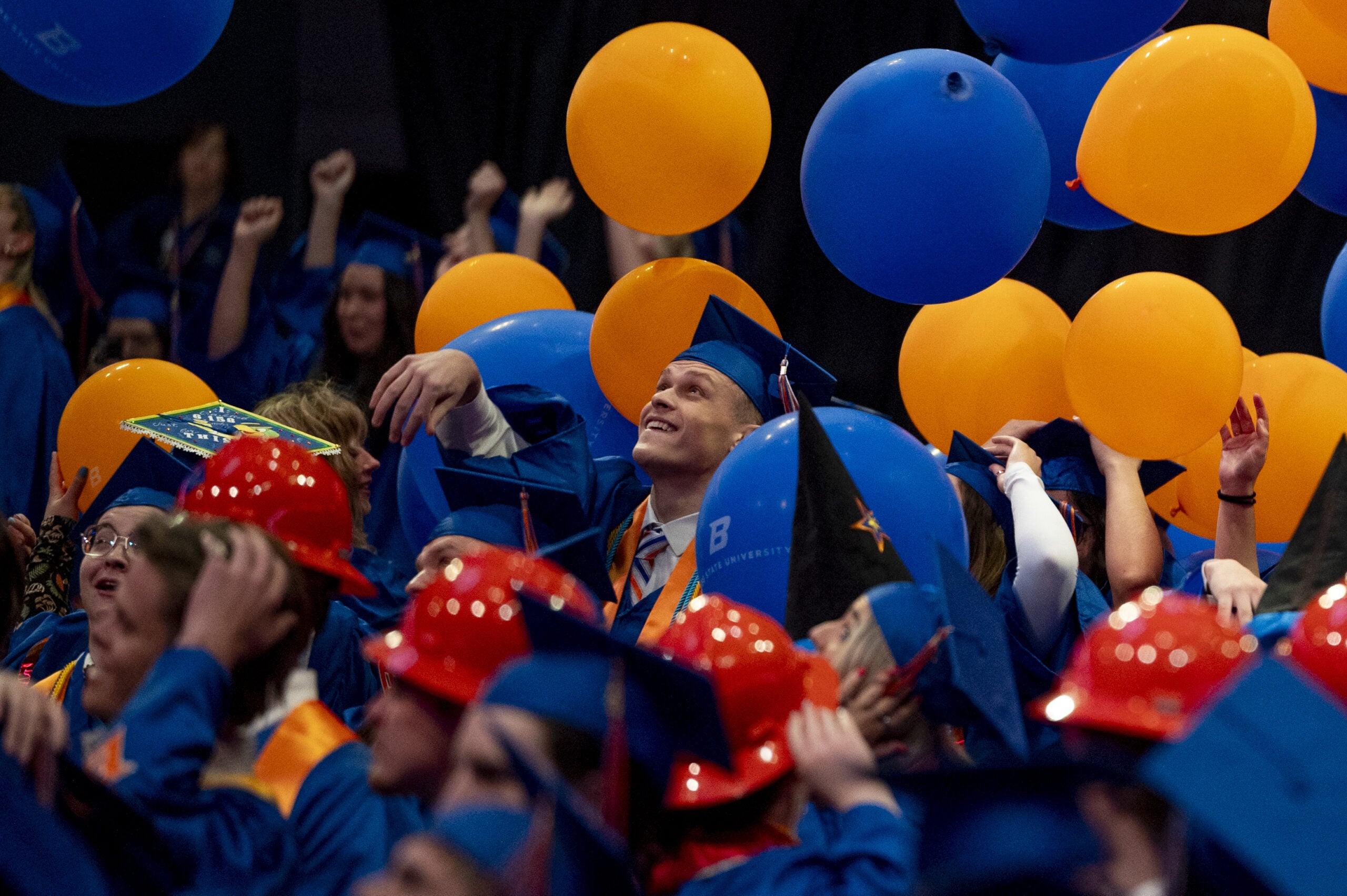 students look up as blue and orange balloons fall from above