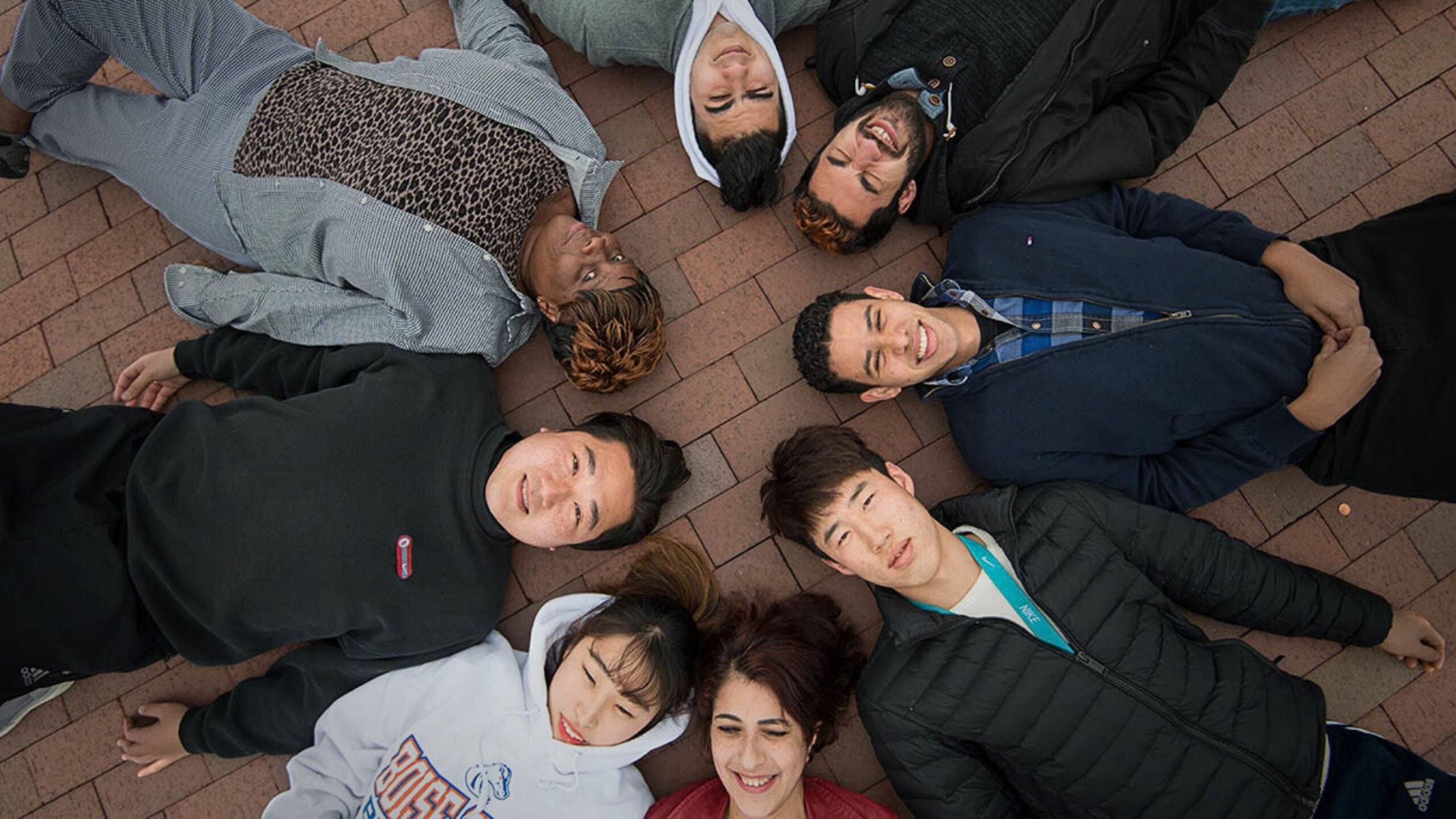 We see a diverse group of people laying in a circle with their heads together, symbolizing that networking brings people together.