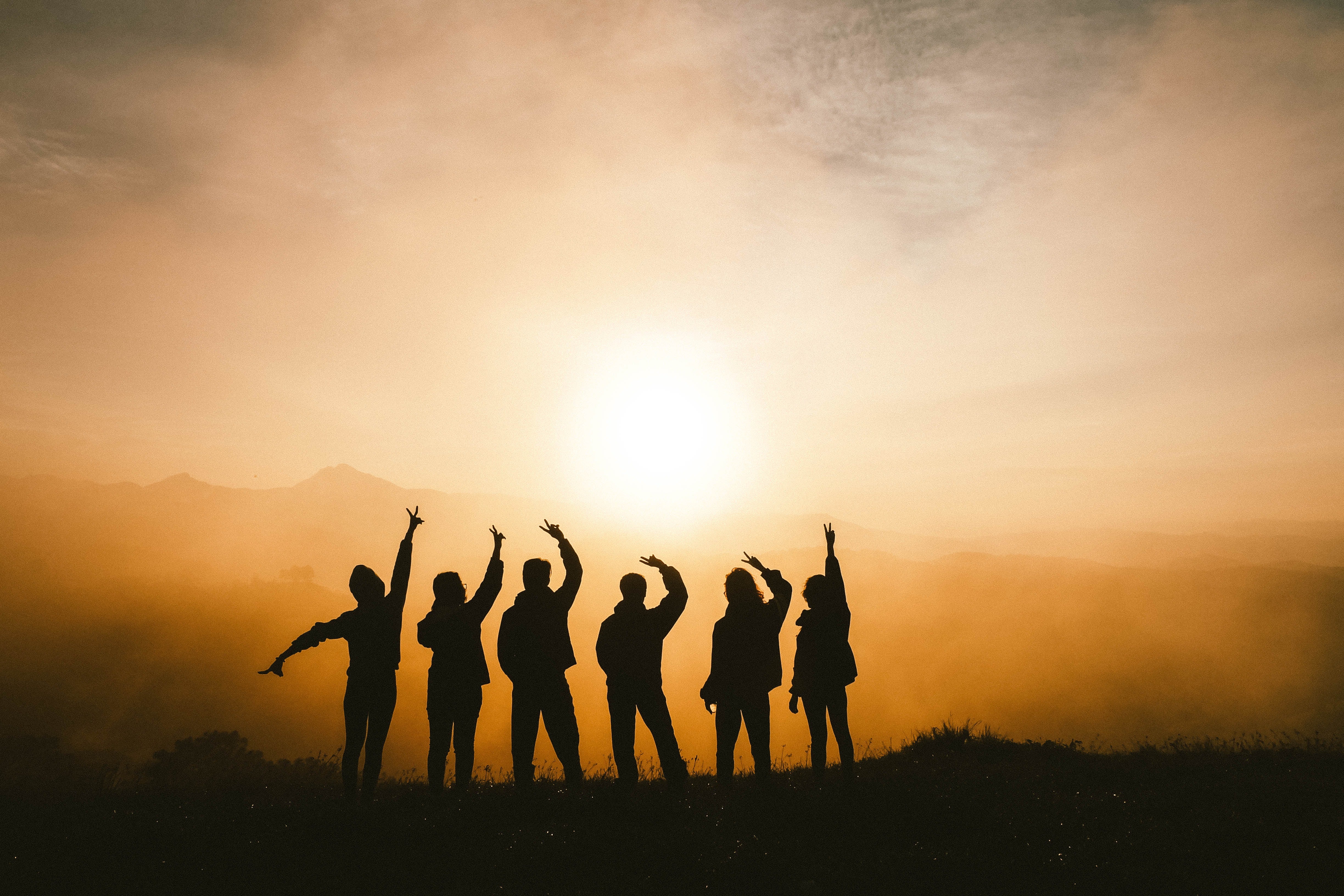Group of people are silhouetted against the sun
