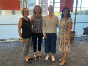 Four women stand together and pose. From left to right: Megan Frary, Teresa Focarile, Sarah Lausch, and Christina Nava.