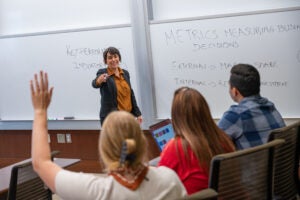 A teacher points to a student with their hand raised.