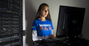 A woman uses a computer while the light from the screen shines on her face.