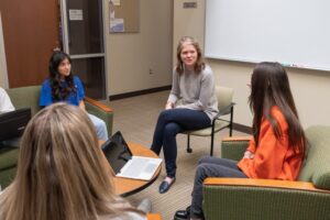 Four people sit in a circle talking to each other. 