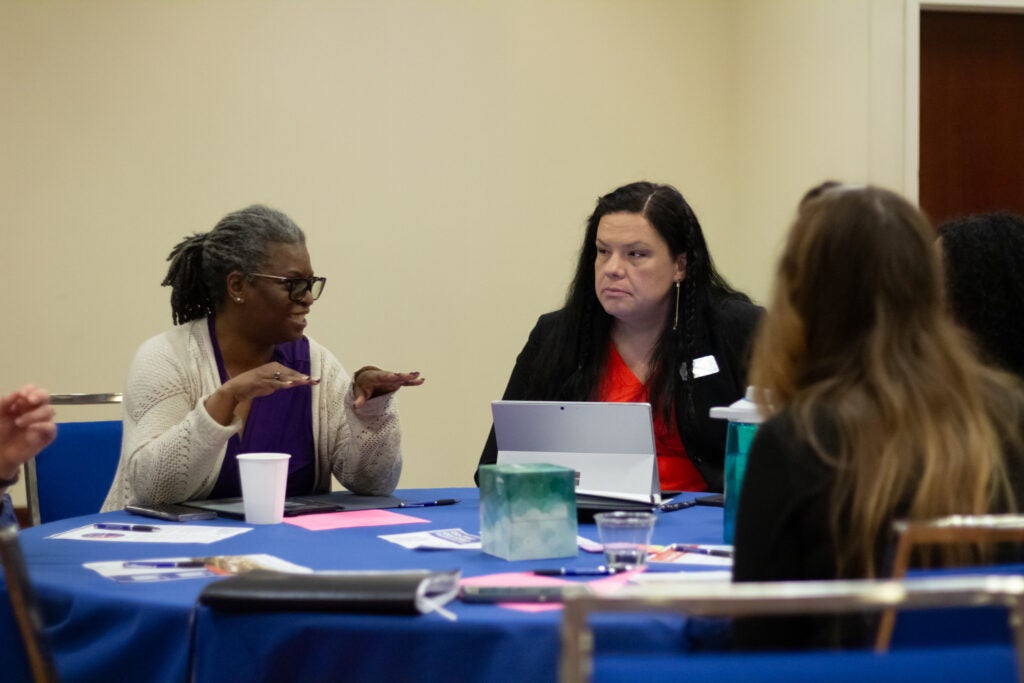 Three people sit and talk at a table. 