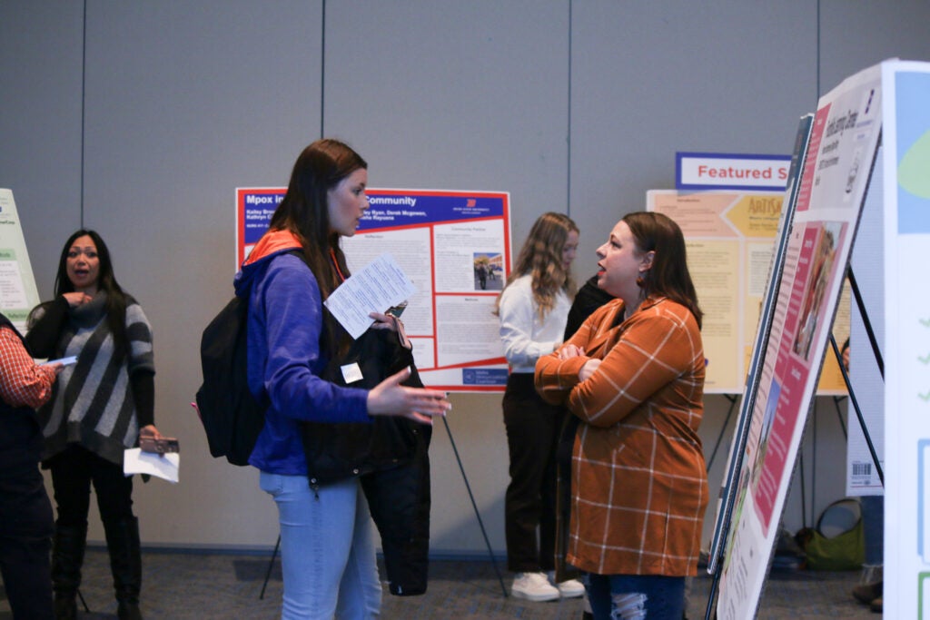 Two people stand together and talk at an expo.