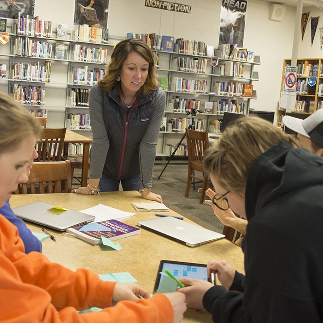 Teacher working with students at a table using an ipad