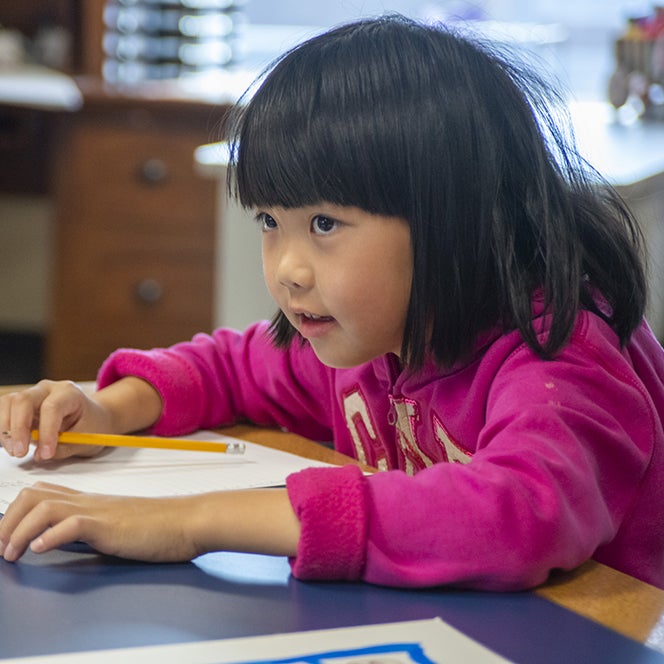 Elementary student at a table with paper