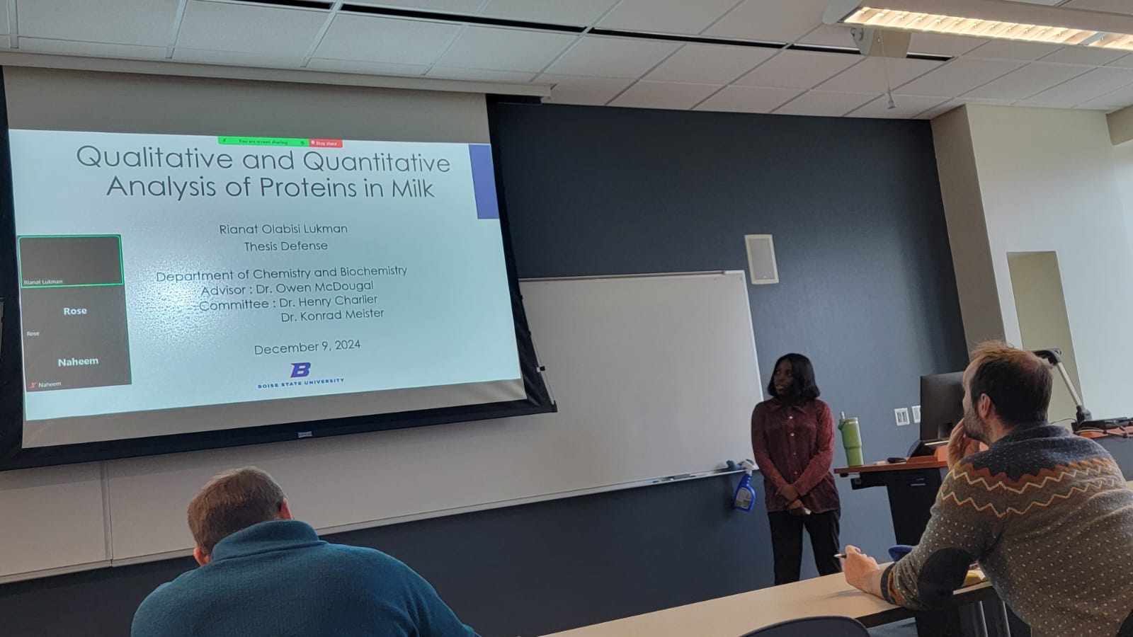 Photo of Rianat Lukman with her title slide for her thesis defense, "Qualitative and Quantitative Analysis of Proteins in Milk"