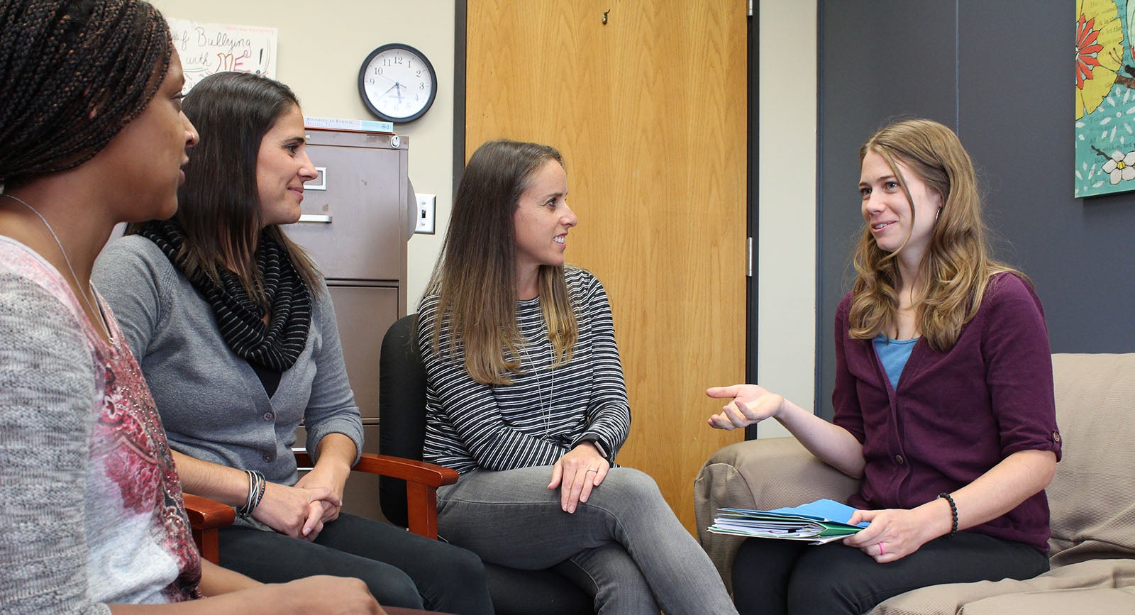 Counselor sitting on sofa in discussion with three clients