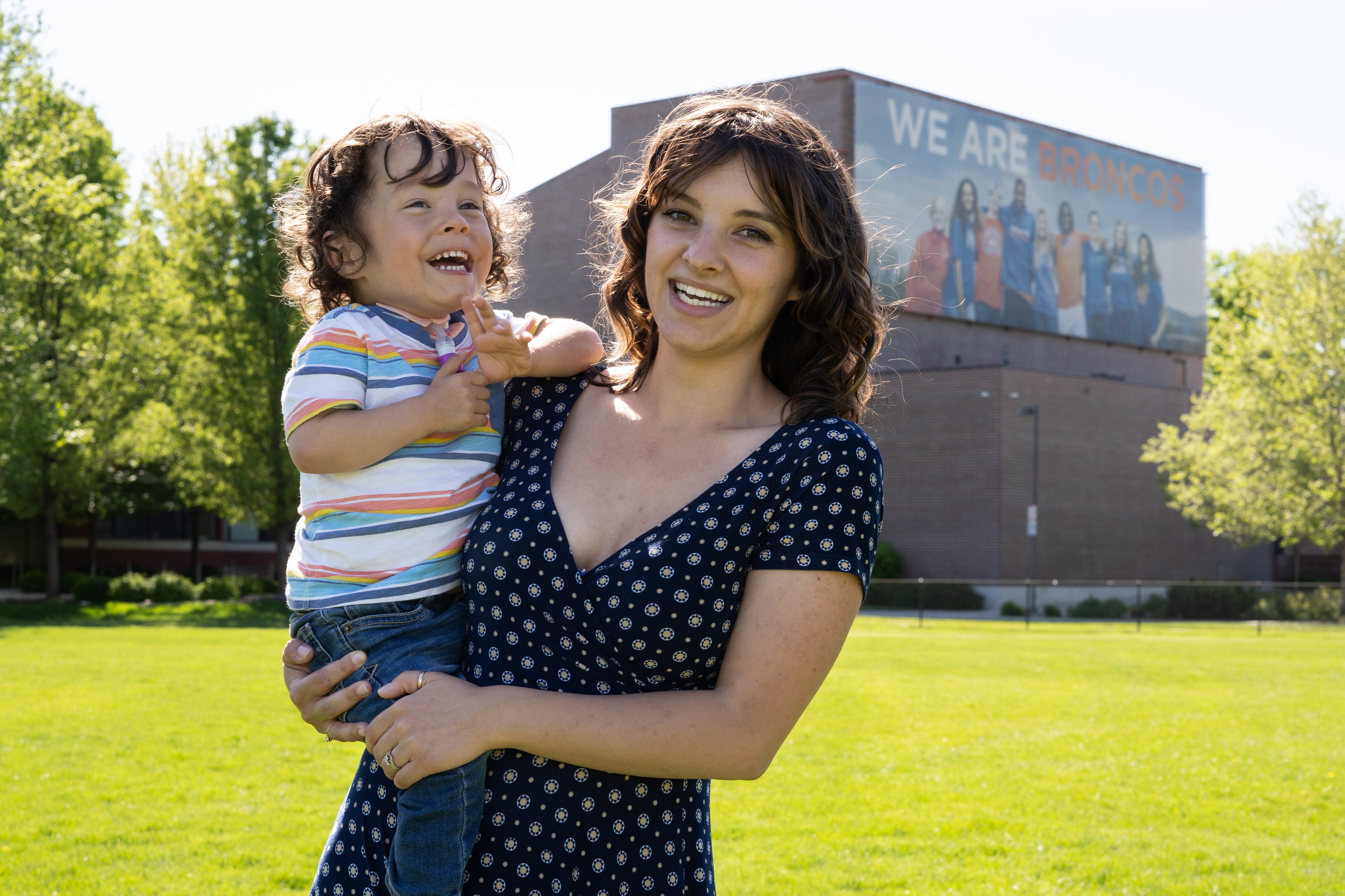 Emma Ballantyne holds her son with We Are Broncos billboard in background