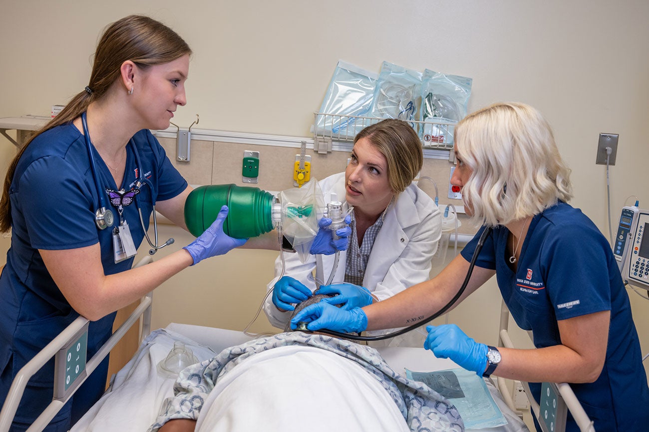 Two students work with faculty to intubate manikin