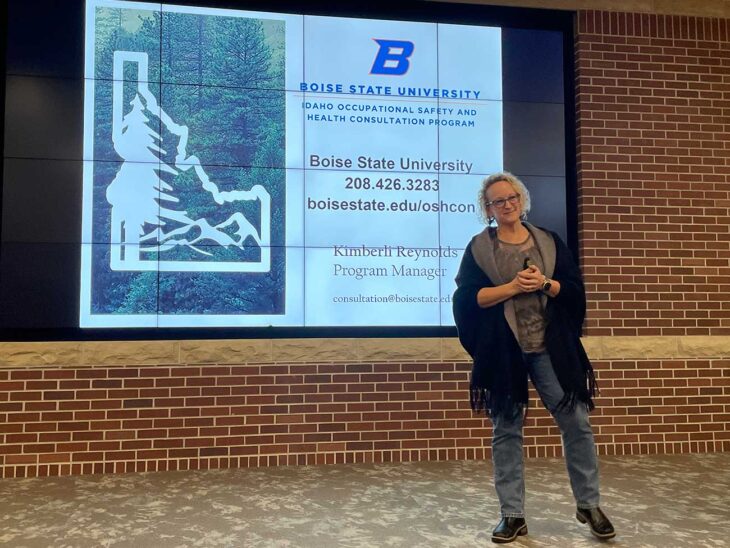 Kimberli Reynolds leads a training for a small business in front of brick wall and projector screen