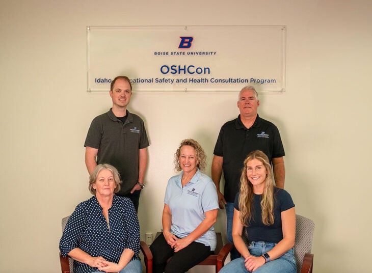 The five members of the Idaho Occupational Safety and Health Consultation team pose with their sign outside their office space.