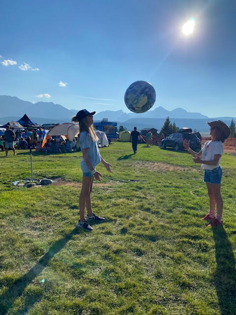 Two people playing with an inflatable Earth ball outdoors