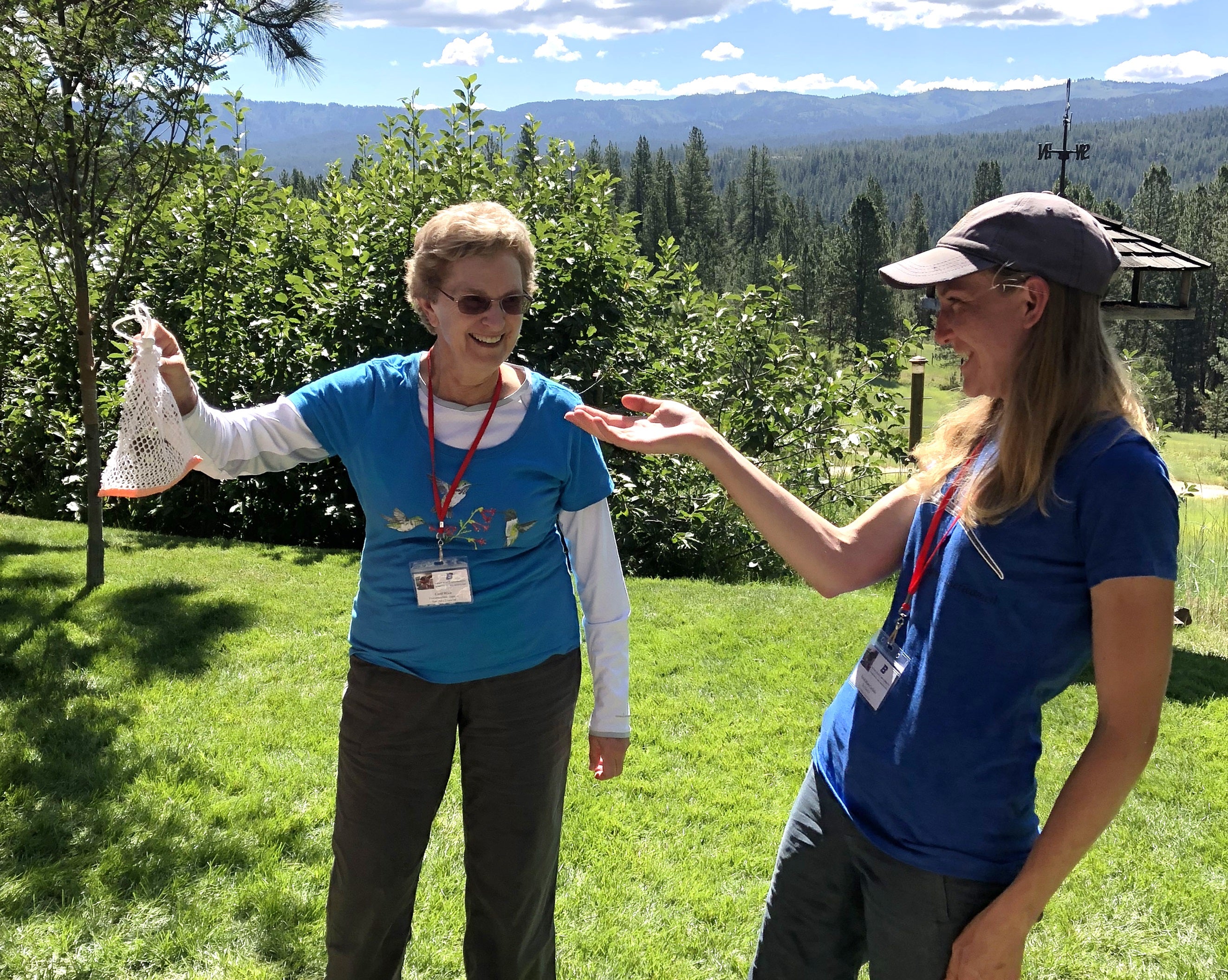 Carol holds a cloth bag high in the air. A small hummingbird can be seen inside