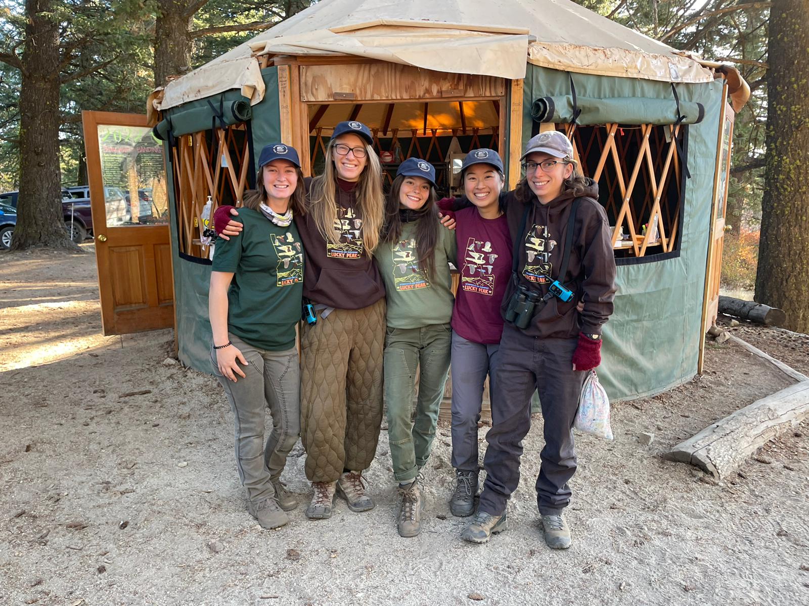 biologists standing in front of a yurt outside in the forest.