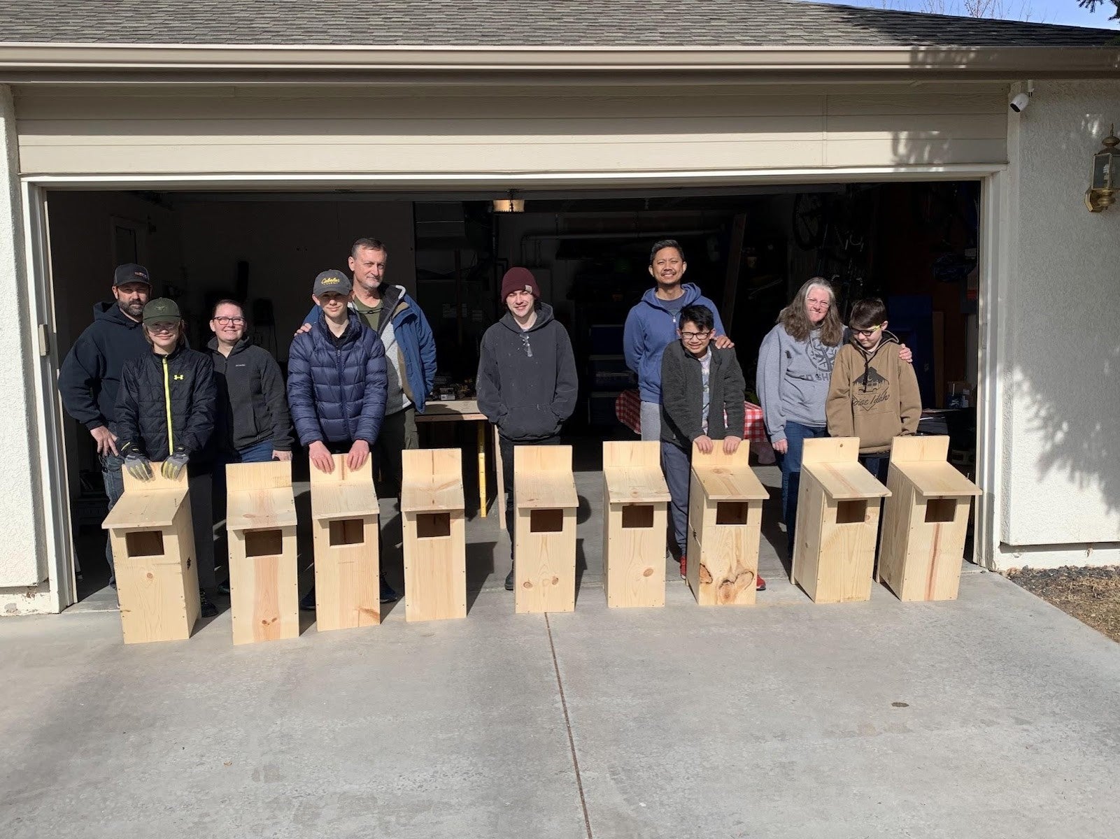 a group of scouts and parents standing, displaying their wooden nesting boxes they built