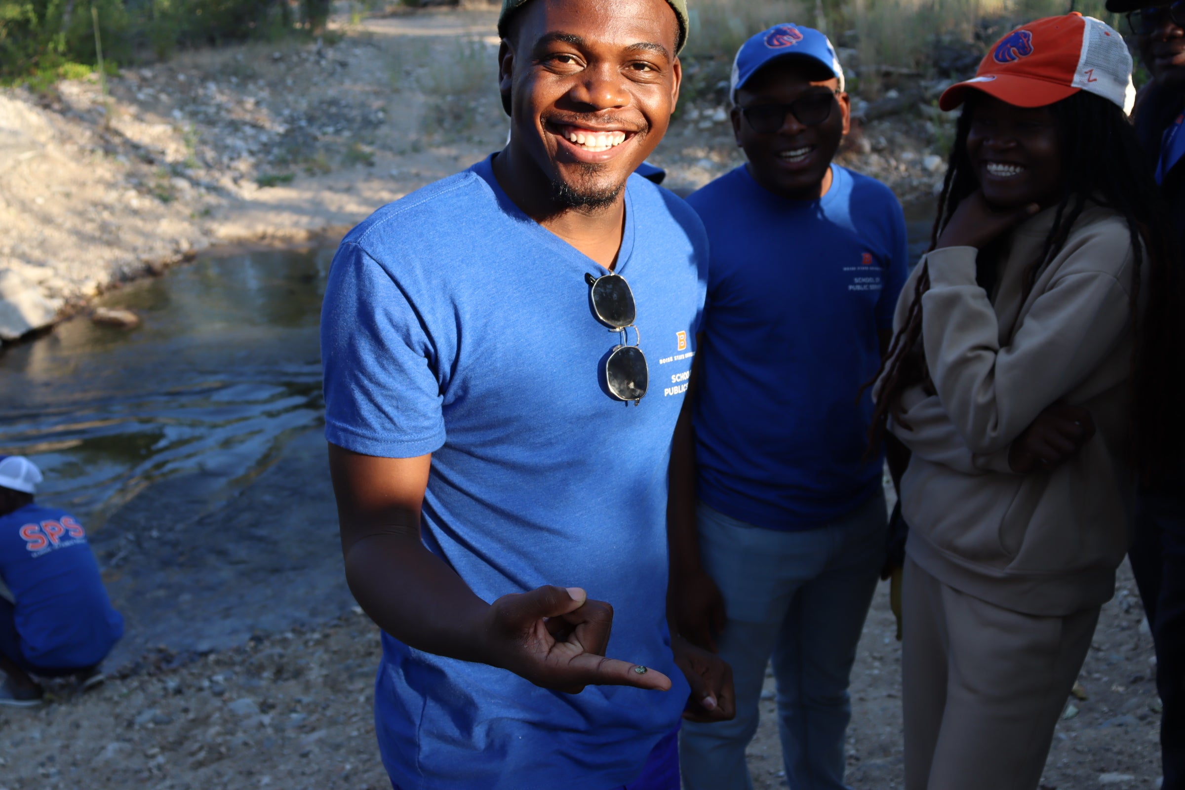 a young man stands grinning at the camera with an outstretched finger. A tiny bird poop sits on his fingertip!