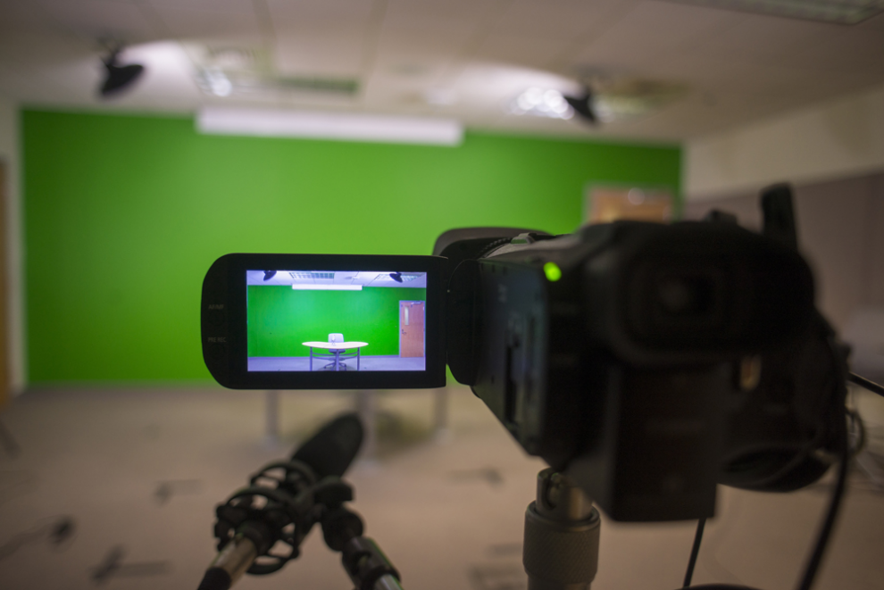 Video camera focused on a desk sitting in front of a green screen
