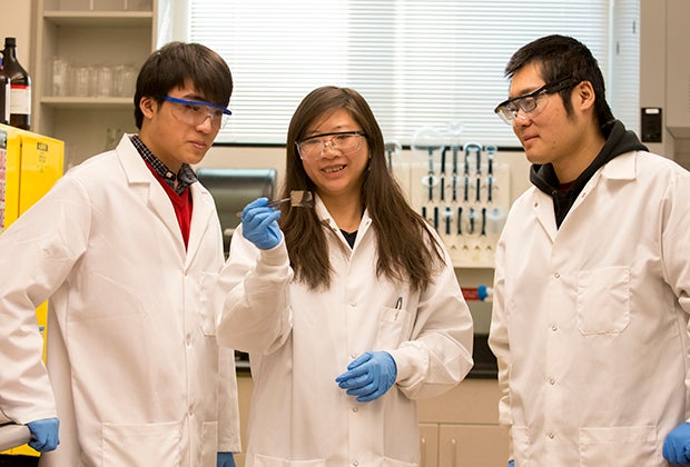 Faculty stands with students in a lab