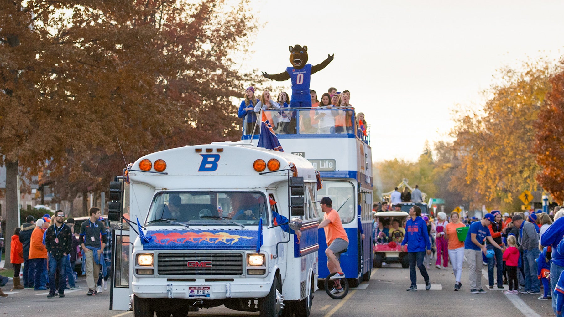 Homecoming photo with a Bronco Shuttle in front, a tour bus behind it with Buster Bronco, and a crowd of people behind that