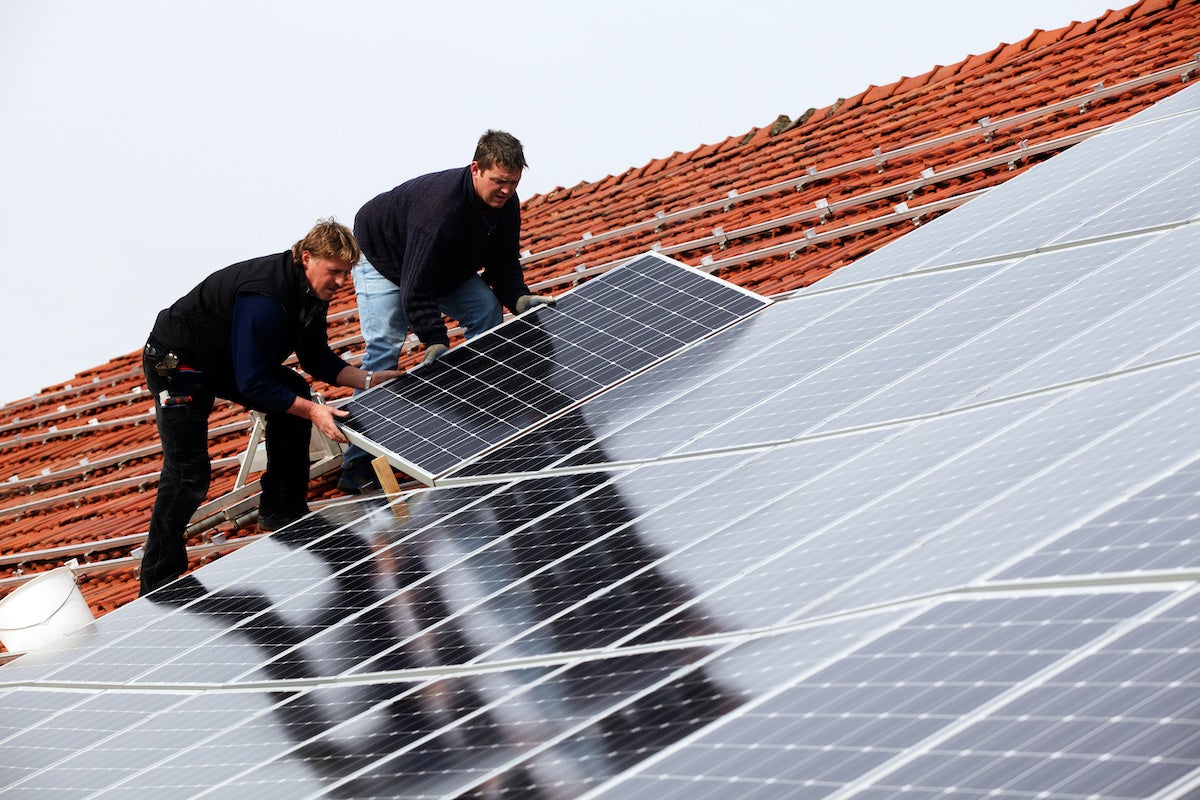 men installing solar cells on roof