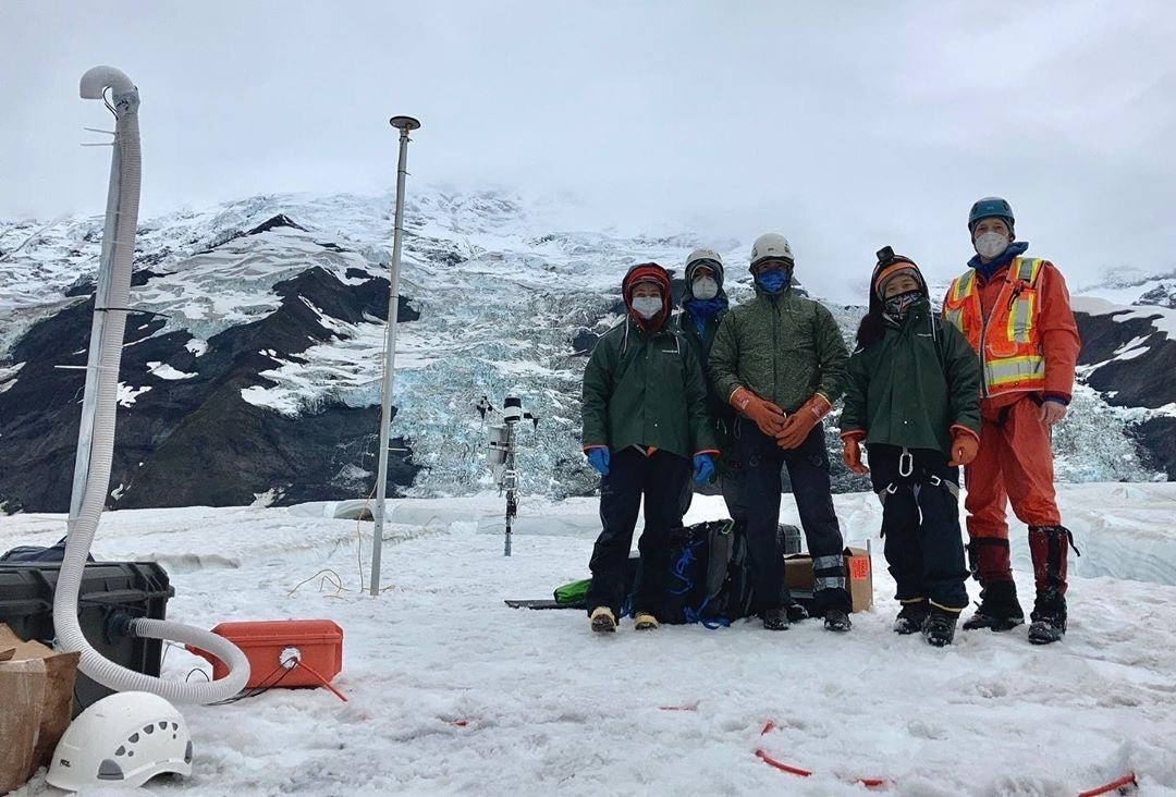 group of researchers pose on glacier