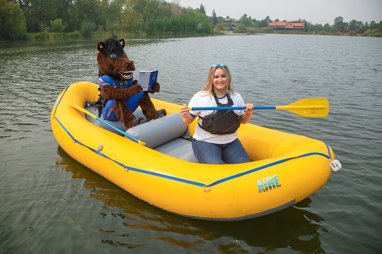 Student and Buster Bronco in a raft.