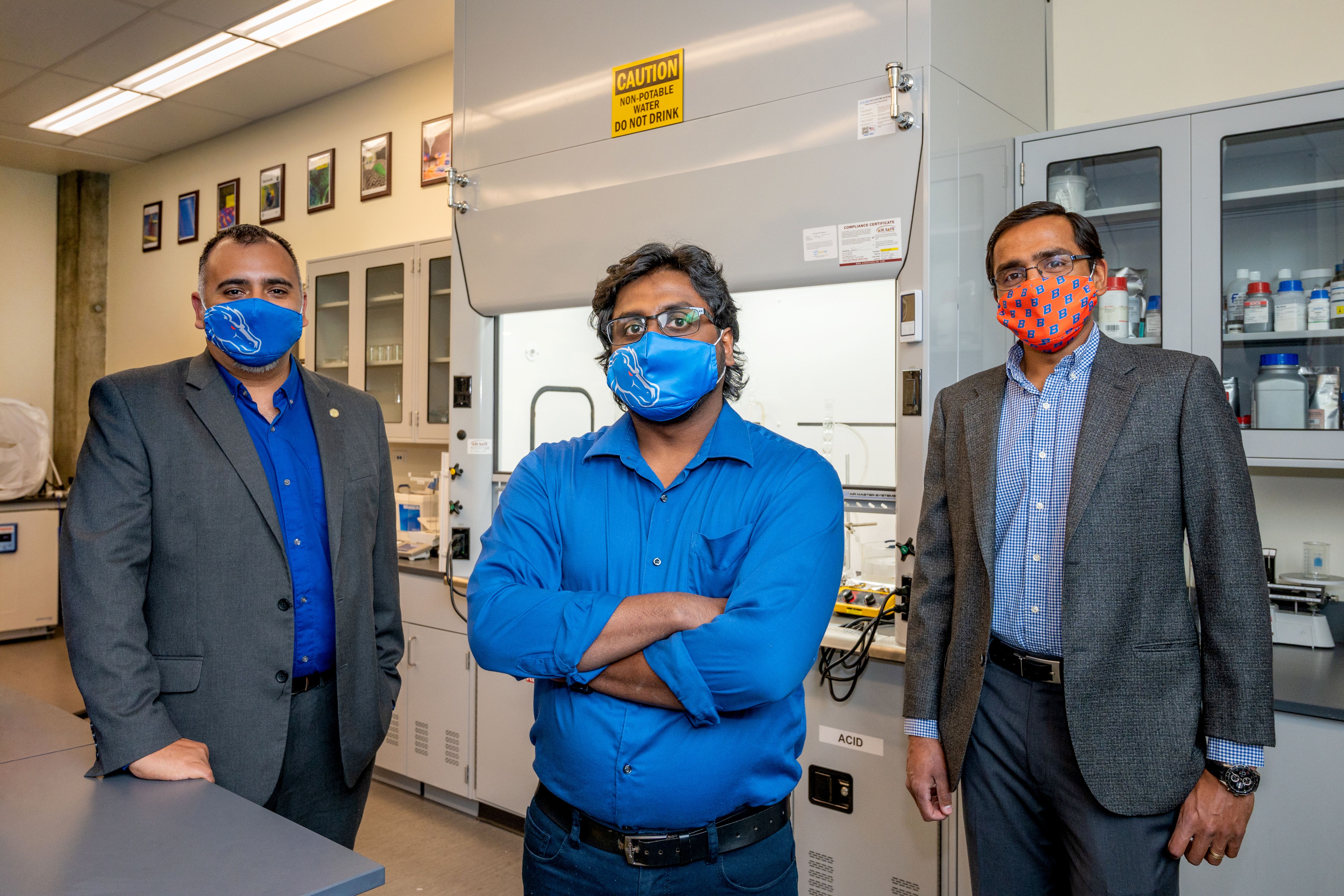 three men stand in lab