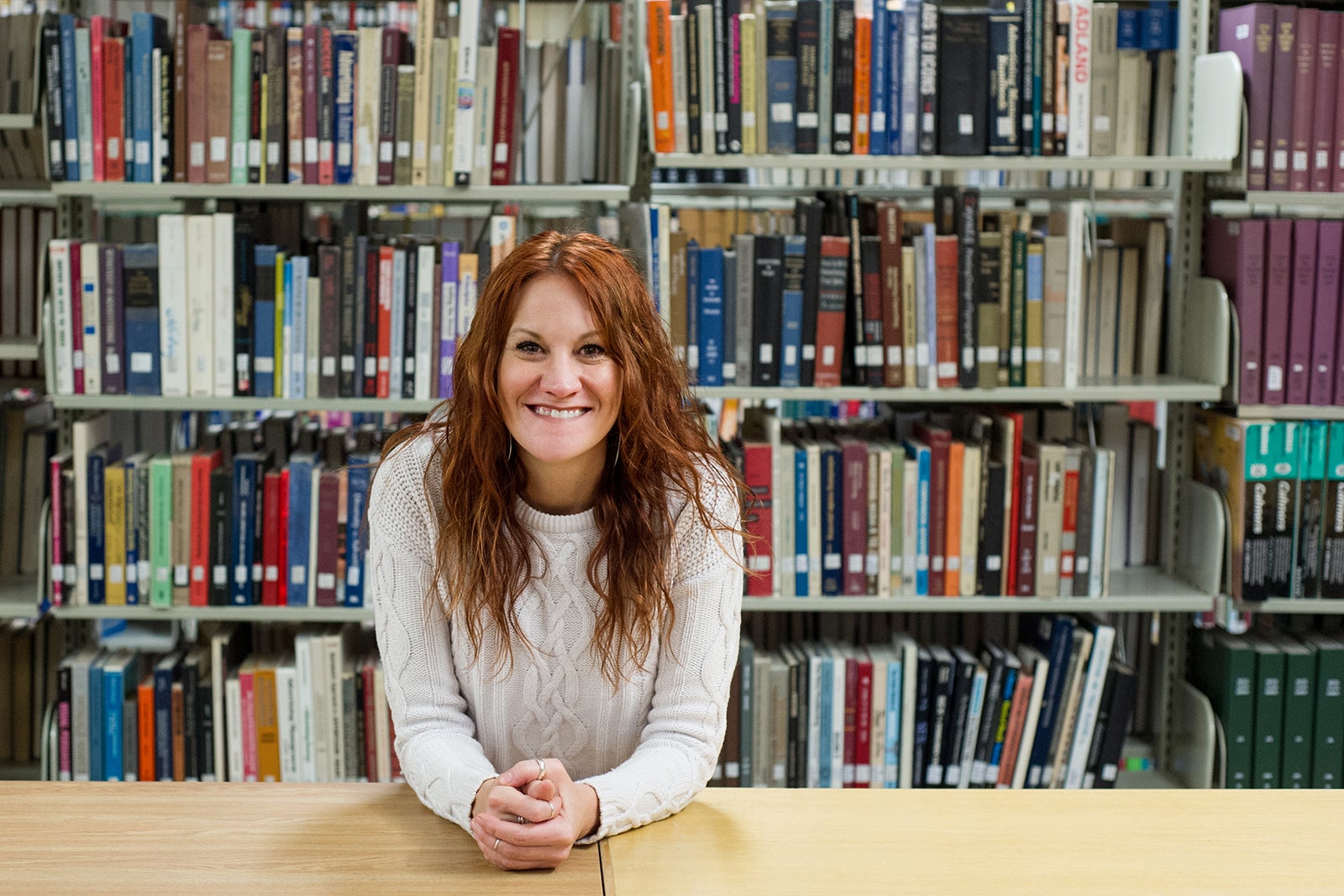 woman sits at table in library