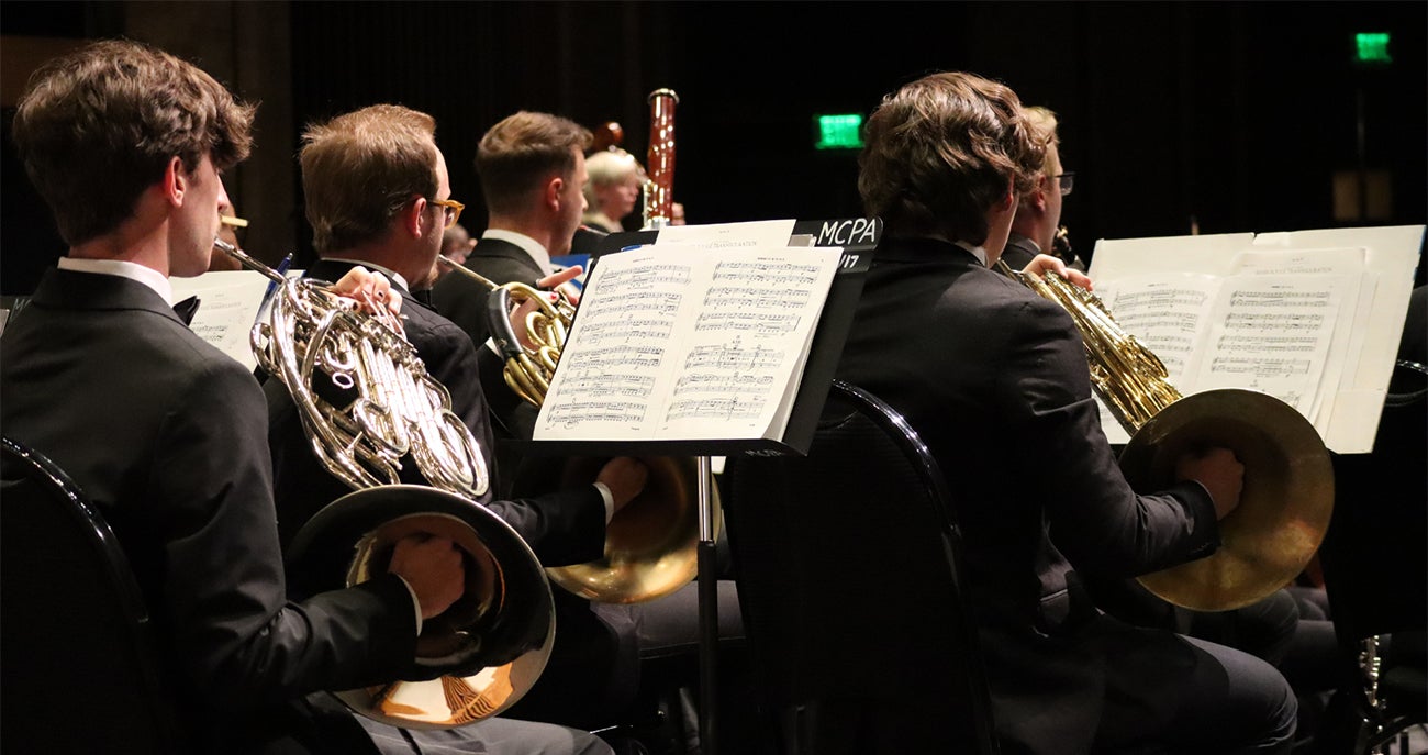 Boise State students performing on French horns during an orchestra concert