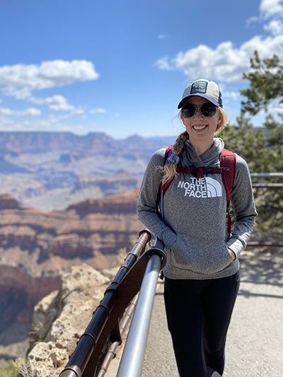 woman stands next to guard rail at Grand Canyon