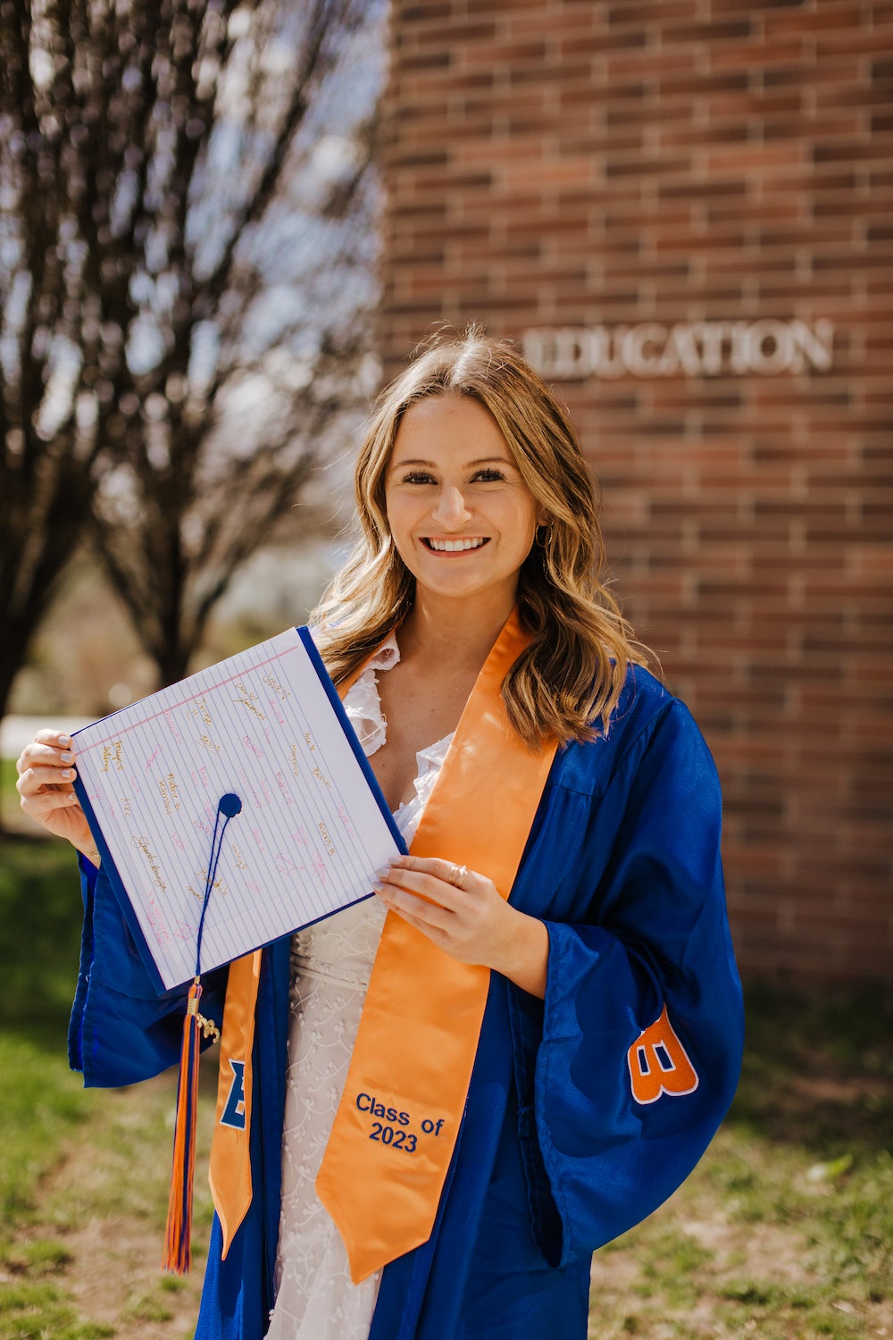 Emily Hawley poses in her Boise State regalia in front of the College of Education building