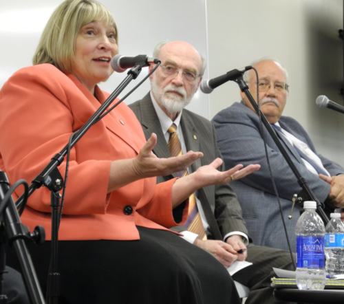 Three panel members at a discussion with Dr. Jim Weatherby in the center listening to another member speak