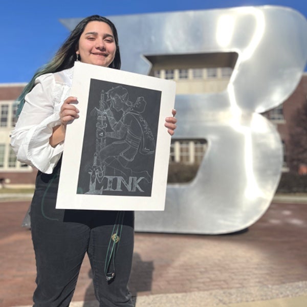 A person holds artwork in front of B Plaza