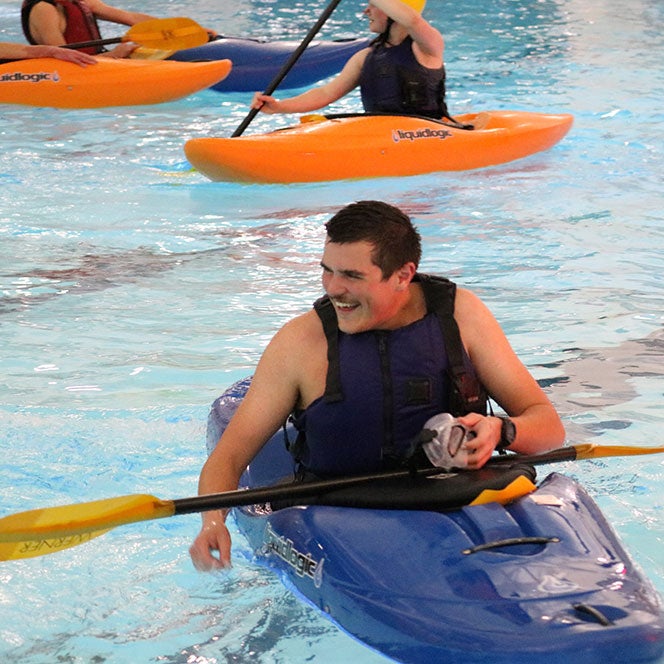 Student in blue kayak in pool